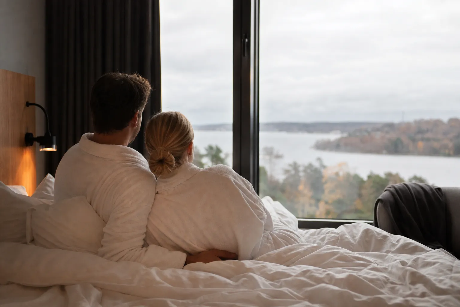 Uppbäddad hotellsäng med champagne på is och rosor inför en romantisk weekend